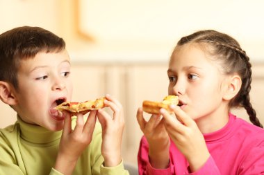 Çocuklar pizza yiyor.  