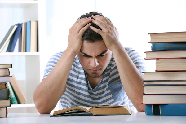 Young man reading book at table — Stock Photo, Image