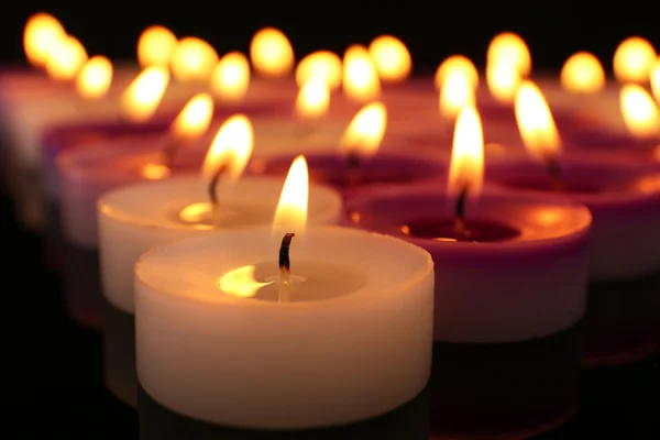 Molte piccole candele accese su sfondo scuro, primo piano — Foto Stock