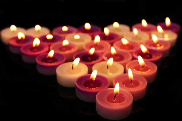 Molte piccole candele accese su sfondo scuro — Foto Stock