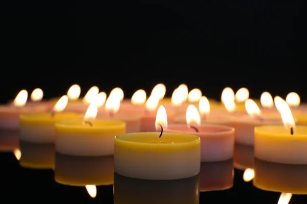 Viele brennende kleine Kerzen auf dunklem Hintergrund, Nahaufnahme — Stockfoto