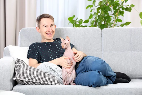 Schöner Mann liegt mit Katze auf Couch — Stockfoto