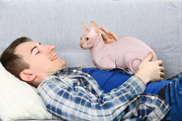 Knappe man ligt met kat op Bank — Stockfoto