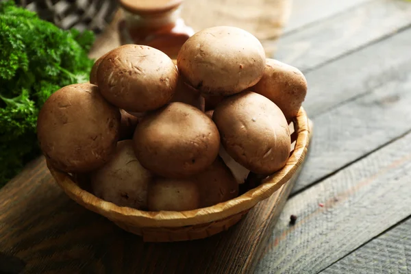 Champiñones en cesta sobre superficie de madera — Foto de Stock