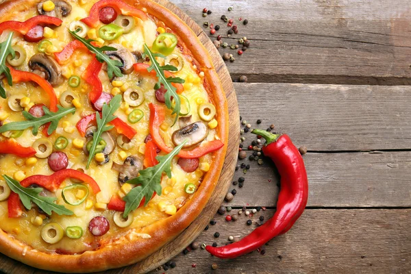 Pizza deliciosa com pimenta no fundo de madeira — Fotografia de Stock