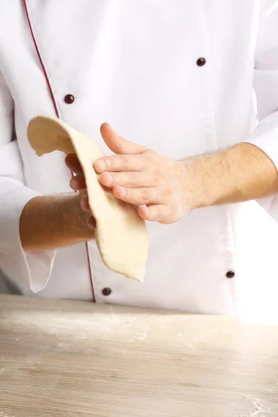 Hands preparing dough basis for pizza on the wooden table, close-up — Stock Photo, Image