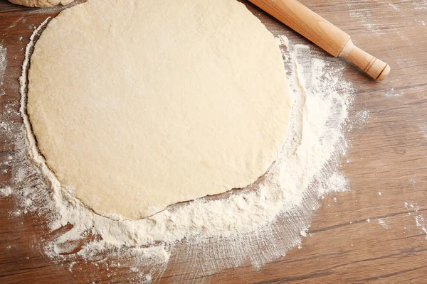 Тесто для пиццы и булавки на деревянном столе — стоковое фото