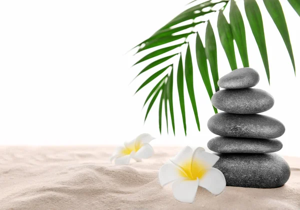 Few spa stones with plumeria on sand, isolated on white — Stock Photo, Image