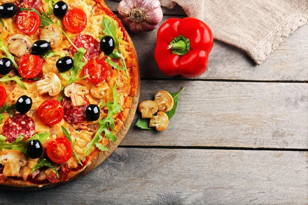 Heerlijke smakelijke pizza met ingrediënten op houten tafel — Stockfoto