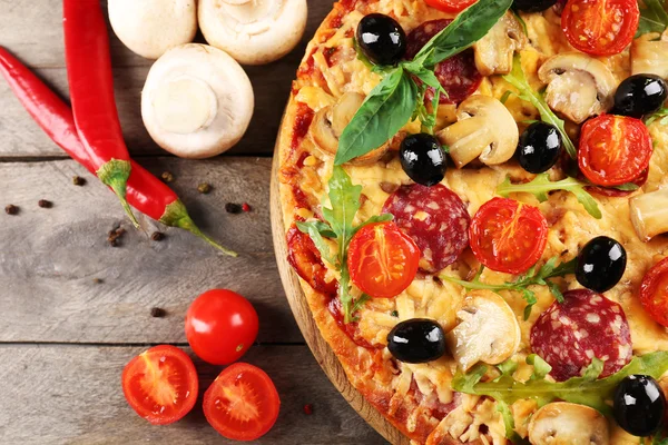 Delicious tasty pizza with ingredients on wooden table — Stock Photo, Image