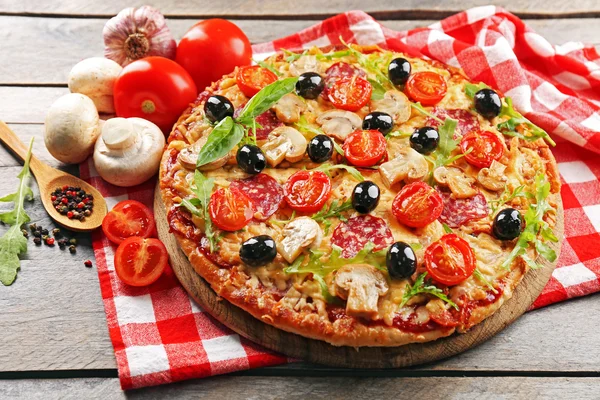 Deliziosa gustosa pizza con ingredienti sul tavolo di legno — Foto Stock