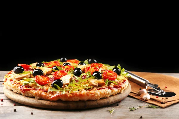 Delicious tasty pizza with cutter on black background — Stock Photo, Image