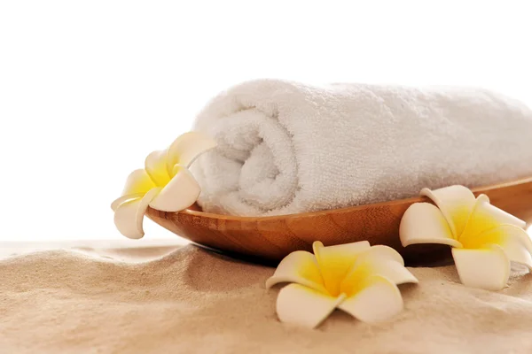 Spa towel with plumeria and bamboo on sand, isolated on white Stock Picture