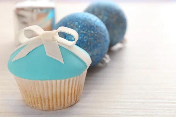 Leckerer Cupcake mit Schleife und Weihnachtsspielzeug auf farbigem Holzhintergrund — Stockfoto