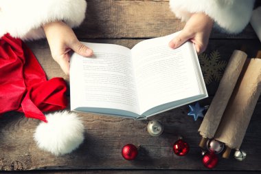 Noel kavramı. Kitap ve Noel dekorasyonları ahşap masa üzerinde Santa elleriyle yakın çekim