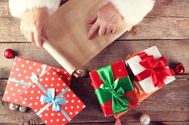 Noel Baba el, hediyeler ve oyuncaklar ahşap arka plan üzerinde Noel listesini istiyor