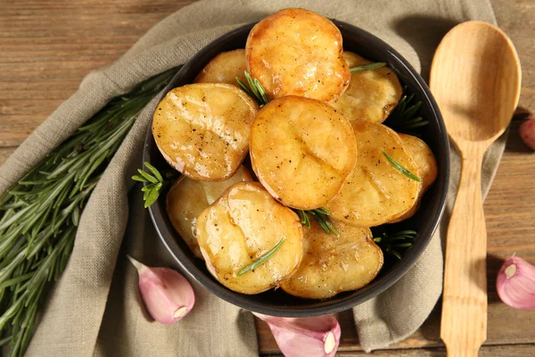 Läckra bakad potatis med rosmarin i skål på bordet på nära håll — Stockfoto