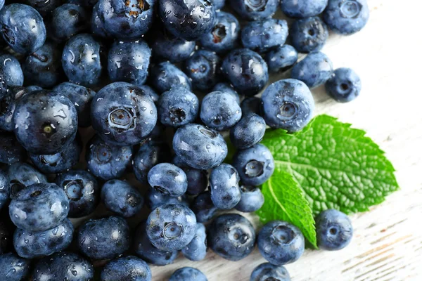 Leckere reife Blaubeeren mit grünen Blättern aus nächster Nähe — Stockfoto