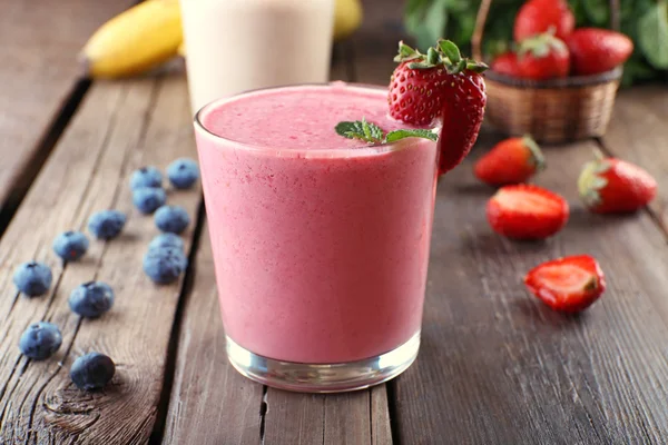 Copos de smoothie frio fresco com frutas e bagas, sobre fundo de madeira — Fotografia de Stock