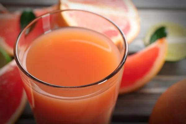 Bicchiere di succo di pompelmo e frutta fresca su sfondo di legno — Foto Stock