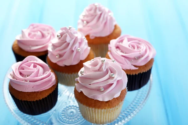 Cupcakes saborosos na cor de fundo de madeira — Fotografia de Stock