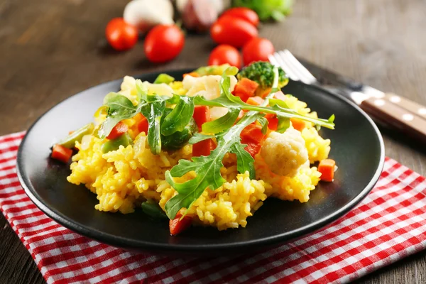 Hizmet ahşap masa üzerinde sebze risotto ile siyah plaka — Stok fotoğraf