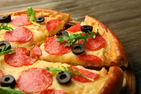 Pizza calda e gustosa con salumi e olive su fondo di legno — Foto Stock