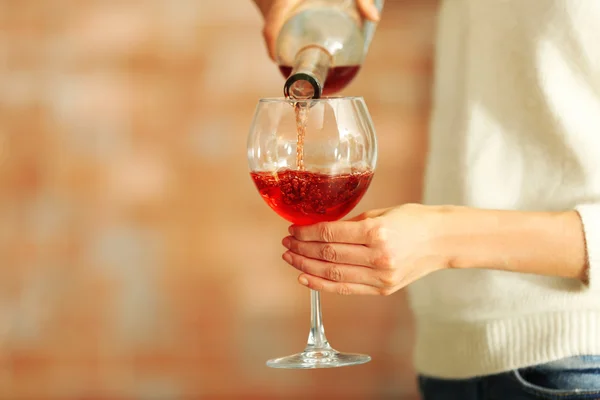 Giovane donna versando vino rosa in vetro su sfondo sfocato — Foto Stock