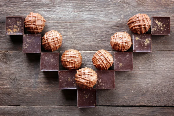 Lekkere chocolade snoepjes op houten achtergrond. V-vormige — Stockfoto