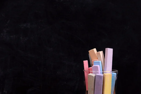 Glass of coloured chalk on blackboard background — Stock Photo, Image