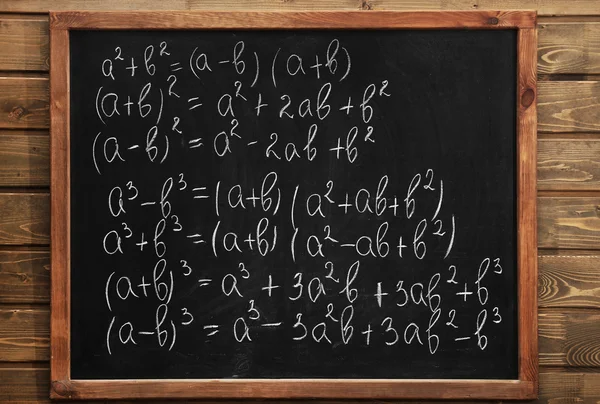 Tableau noir scolaire avec des formules sur un mur de briques — Photo