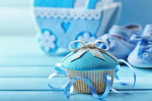 Sabrosos cupcakes con arco y zapatos de bebé, carruaje de bebé decorativo y álbum de fotos en el fondo de color —  Fotos de Stock