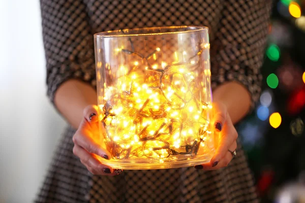 Jar with garland in hands — Stock Photo, Image