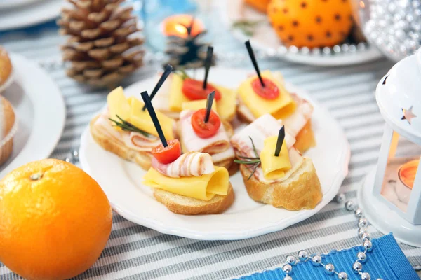 Canapés com queijo, carne e tomate em um jantar de mesa de Natal, close-up — Fotografia de Stock