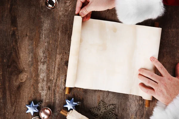 Uma lista de desejos de Natal em mãos de Papai Noel em fundo de madeira — Fotografia de Stock