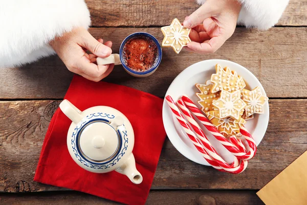 クリスマスのコンセプトです。サンタは、食事をしています。おいしいクッキーと木製の背景にコーヒーのカップをクローズ アップ — ストック写真
