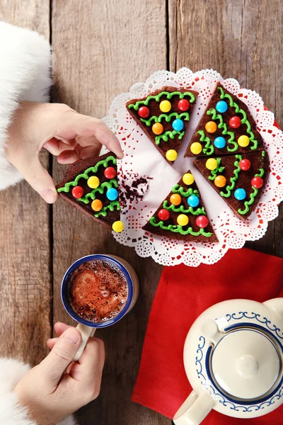 Christmas concept. Santa have a meal. Tasty chocolate cake and cup of coffee on wooden background, close up