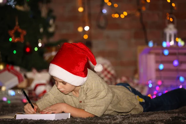 Jongen schrijven in notitieblok op een kerstfeest — Stockfoto