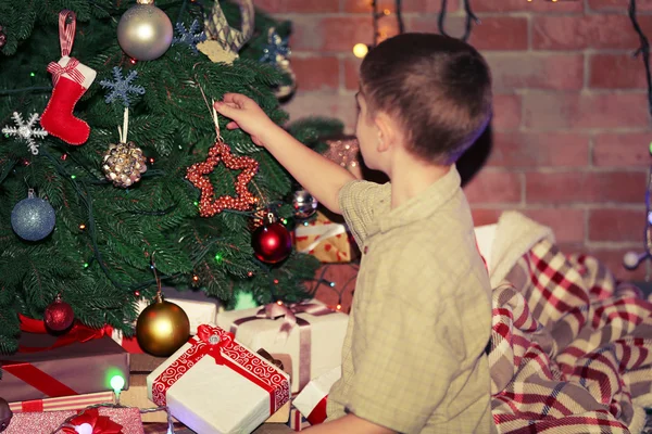 Boy hanging toys on a fir tree — Stock Photo, Image