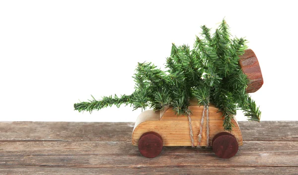 Wooden toy car with Christmas tree on a table over white background — Stock Photo, Image