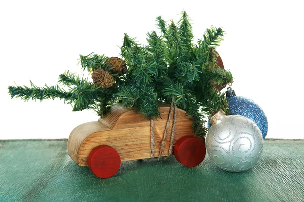 Macchina giocattolo in legno con albero di Natale e bagattelle su un tavolo su sfondo bianco — Foto Stock