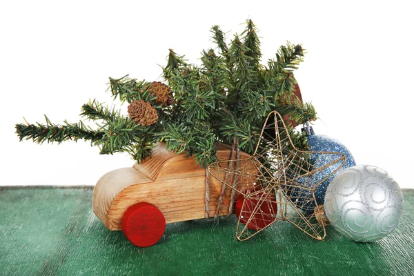 Carro de brinquedo de madeira com árvore de Natal e brinquedos em uma mesa sobre fundo branco — Fotografia de Stock