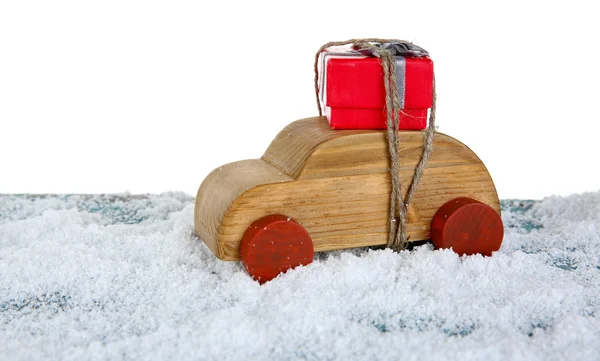 Деревянный игрушечный автомобиль с подарочной коробкой на снежном столе на белом фоне — стоковое фото