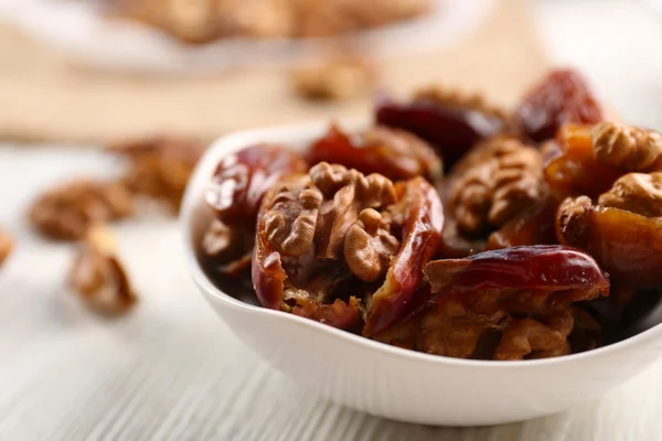 Walnut and date fruit in plate on wooden table, close-up — Stock Photo, Image