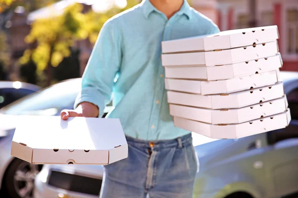 Pizzabote hält Kisten mit Pizza in der Nähe von Auto — Stockfoto