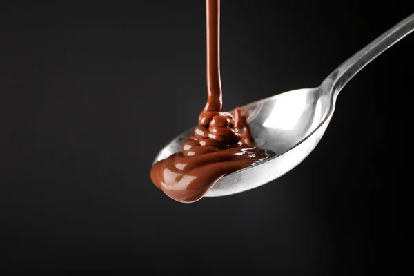 Chocolate poured on a spoon on dark background — Stock Photo, Image