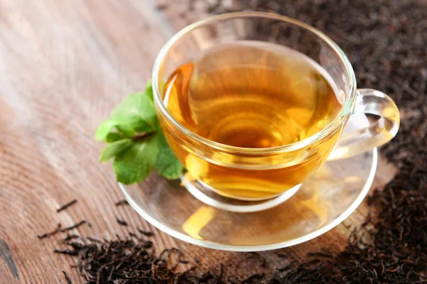 Üveg csésze zöld tea levelek, fából készült háttér díszíti szétszórt tea — Stock Fotó