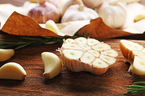 Composition of garlic and rosemary on the kitchen board, close up — Stock Photo, Image
