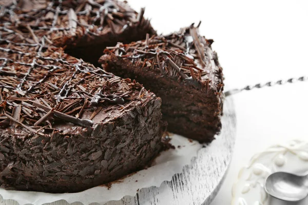 Bolo de chocolate fatiado na mesa de madeira, no fundo claro — Fotografia de Stock