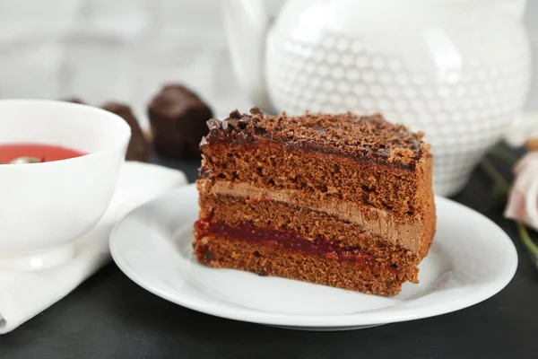 Sliced chocolate cake on plate, on wooden table  background — Stock Photo, Image